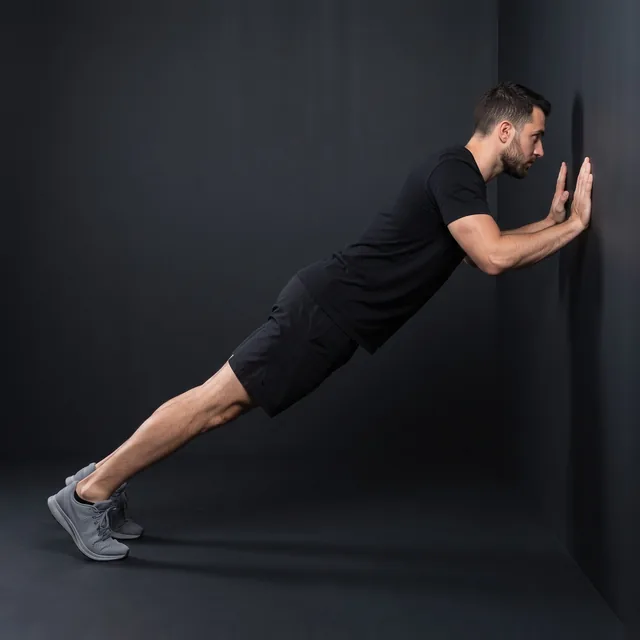 A person doing close-grip wall push-ups