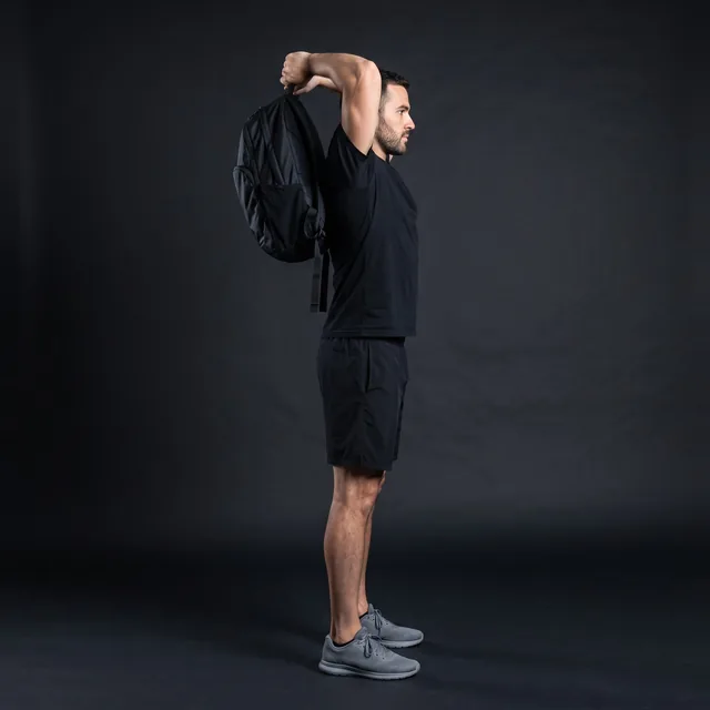 A person doing overhead triceps extension (backpack)
